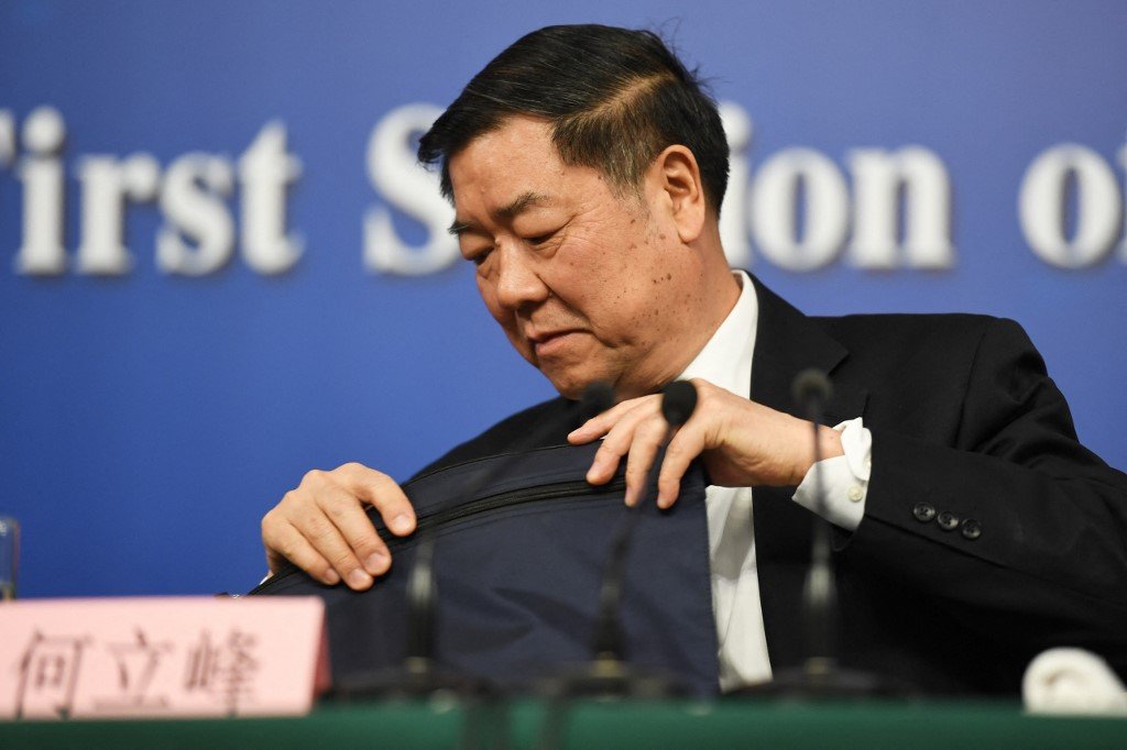 圖為2018年3月，中共國家發改委主任何立峰在新聞發布會上準備文件。（AFP）