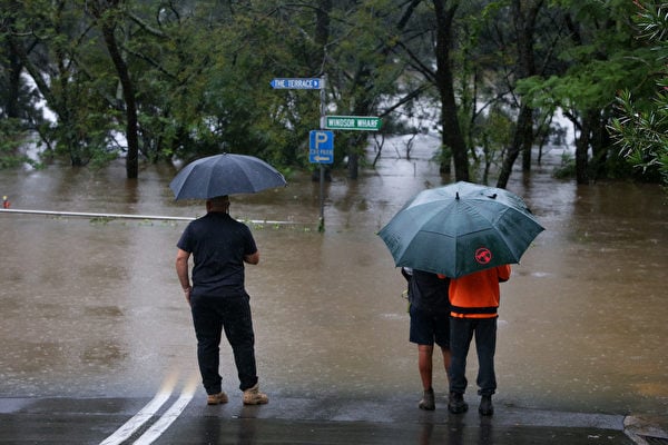 2021年3月22日，澳洲悉尼，霍克伯里河（Hawkesbury River）氾濫成災，三位民眾看著被水淹沒的道路。（Lisa Maree Williams/Getty Images）