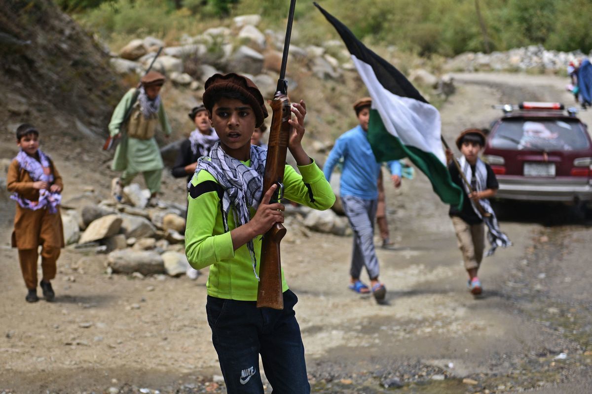 2021年8月21日，在塔利班以驚人的速度接管阿富汗幾天後，阿富汗當地居民的孩子們扛著獵槍和潘傑希爾全國抵抗陣線（NRF）的旗幟走過潘傑希爾省（Panjshir）達拉區（Dara）班德喬伊（Bandejoy）地區的一條道路。（AHMAD SAHEL ARMAN/AFP via Getty Images）