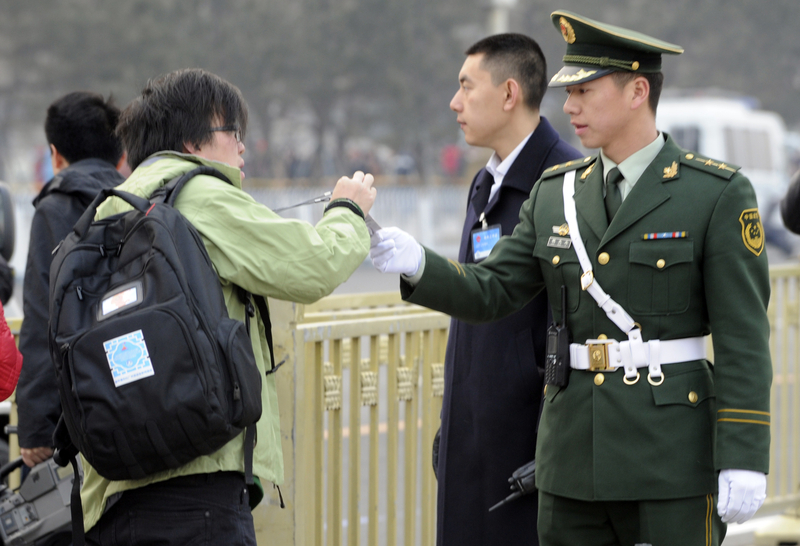 中共兩會召開之際，天安門廣場嚴加盤查。圖為2011年3月5日，北京天安門廣場，警察要求檢查一名記者的證件。（GOH CHAI HIN/AFP）