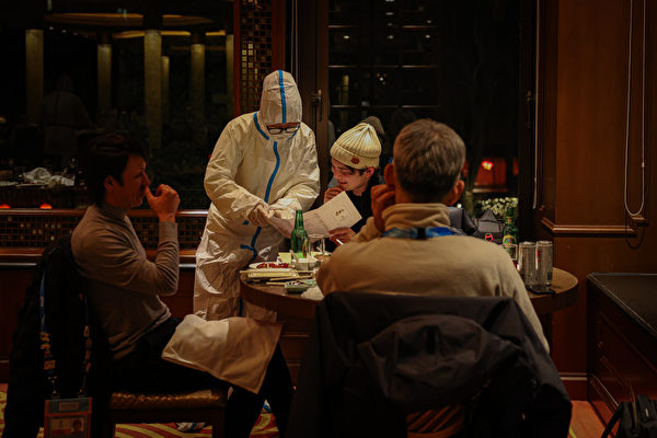 2月10日，北京「閉環泡泡」中一家餐廳，穿防毒服的服務員在幫顧客點菜。（Annice Lyn/Getty Images）