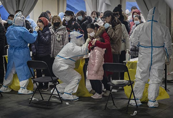 2022年1月24日在北京的一個大規模核酸檢測點，一名身穿防護服的衛生工作給一名女孩進行核酸檢測（Kevin Frayer/Getty Images）