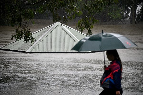 2021年3月21日，澳洲彭里斯（Penrith），豪雨造成尼平河（Nepean river）氾濫成災，一位市民經過被洪水淹沒的公園。（SAEED KHAN/AFP via Getty Images）