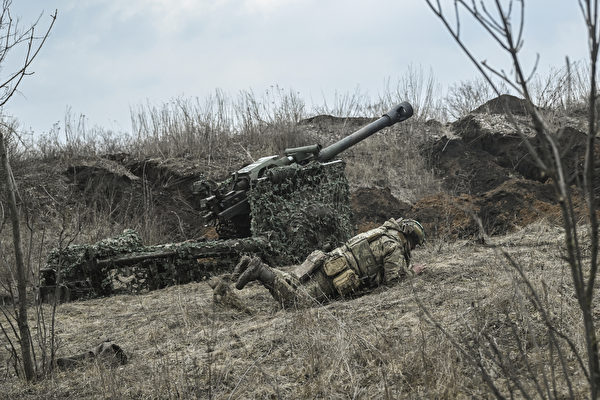 2023年3月8日，巴赫穆特（Bakhmut）附近，在俄烏戰爭期間，一名烏克蘭士兵在炮擊後臥倒尋求掩護，一旁是105毫米榴彈炮。（Aris Messinis/AFP）