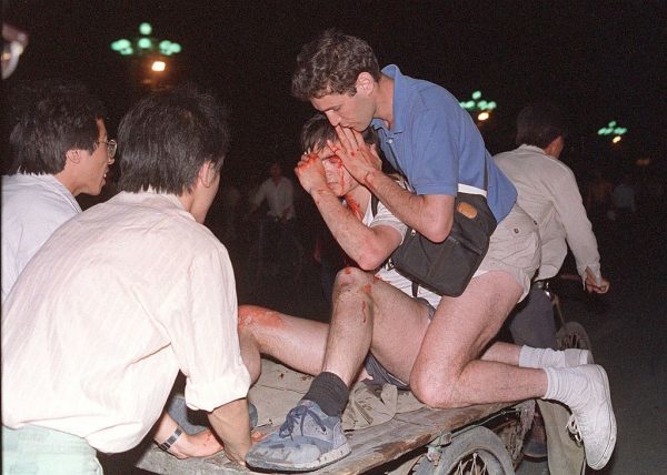 1989年6月4日,一名外國記者(右二)在其他人的照顧下,從天安門廣場附近的軍隊和學生衝突現場被抬出。據國際特赦組織稱,在中共鎮壓中國民主運動五年後,仍有「成千上萬」的囚犯被關在監獄裏。(Tommy Cheng/AFP/Getty Images)
