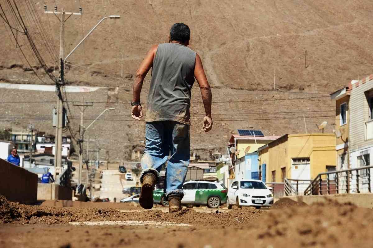 2026年8月19日，智利安托法加斯塔大區（Antofagasta）沿海城市托科皮亞（Tocopilla）因極端暴雨引發嚴重的泥石流災情，一名男子走在滿是淤泥和碎石的街道上。（Jorge Perez/AFP via Getty Images）