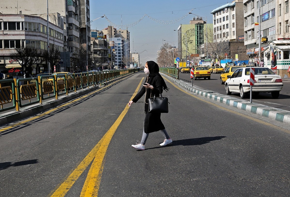 圖為2020年3月4日，一名戴著防護口罩的伊朗婦女穿過首度德黑蘭馬路。（ATTA KENARE/AFP）