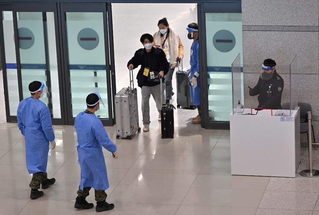 ​2023年1月10日，中共宣布暫停向南韓公民發放短期簽證，以報復南韓對中國旅客的入境限制措施。圖為2023年1月3日，南韓衛生工作者引導從中國抵達的旅客前往首爾以西仁川國際機場的COVID-19檢測中心。（Jung Yeon-je/AFP）