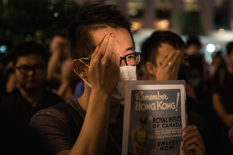 2019年8月30日晚上8點，香港民眾在中環和平紀念碑舉辦重光紀念日默站活動，參與民眾並做出掩右眼手勢。（Chris McGrath/Getty Images）
