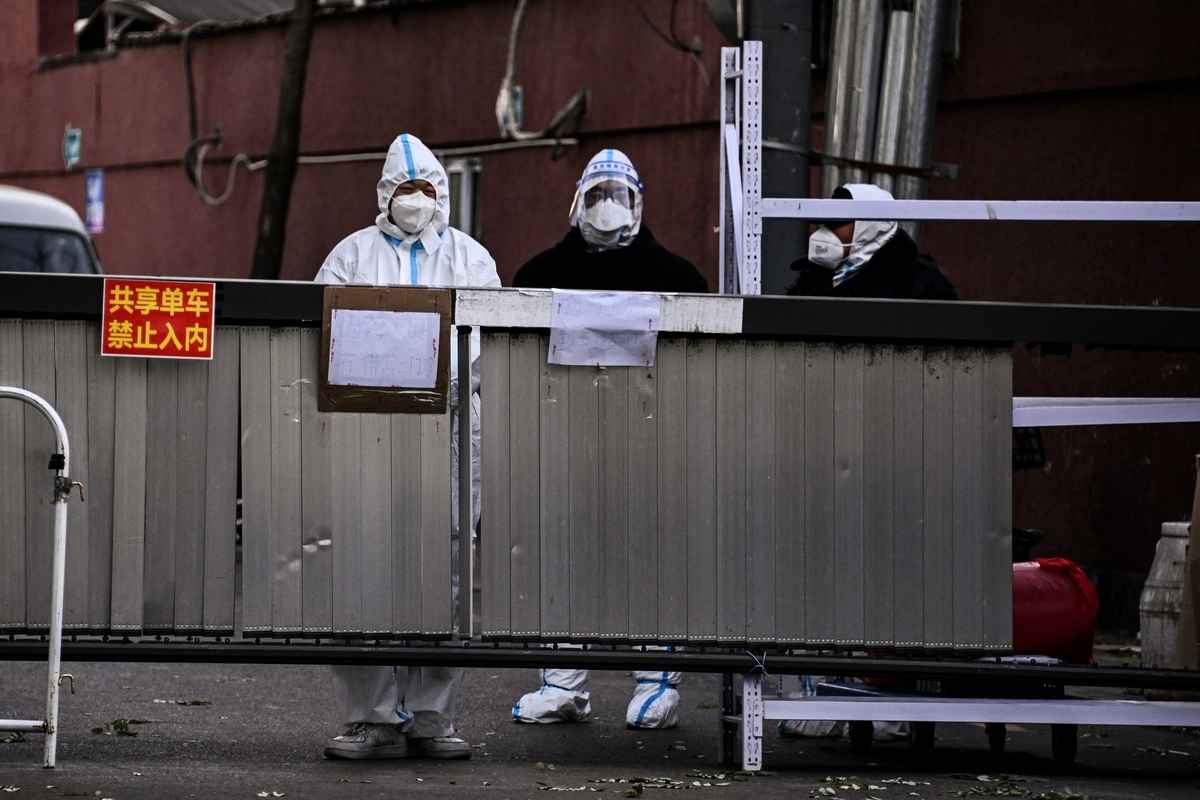 2022年11月29日，由於北京的Covid-19冠狀病毒限制，穿著個人防護裝備 （PPE） 的工人和保安人員守衛著住宅區的入口。（Noel CELIS/AFP）