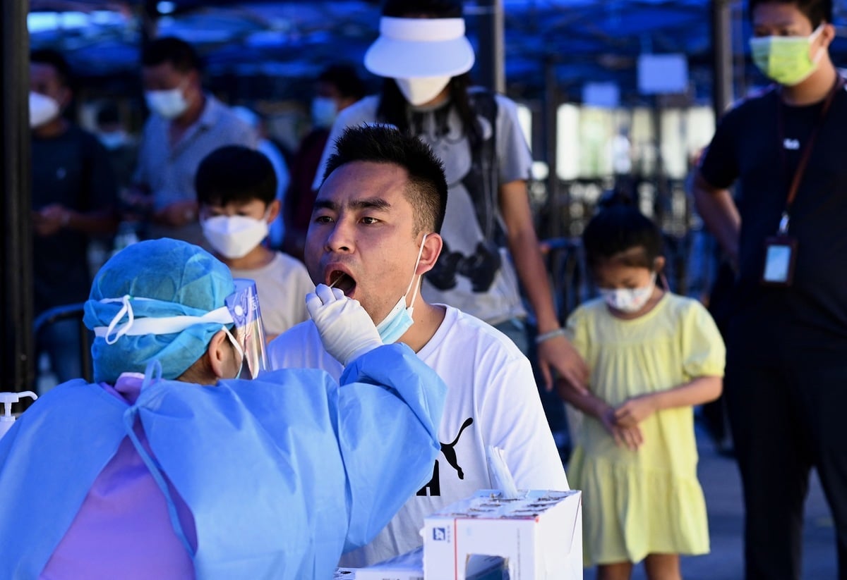 在中國的火車站，一名衛生工作者為到站旅客進行COVID-19病毒的核酸檢測。（Noel Celis/AFP via Getty Images）