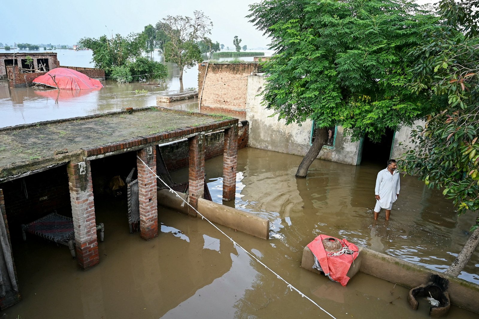 2025年9月3日,大雨導致薩特累季河(Sutlej River)水位上升,旁遮普省卡蘇爾區(Kasur district)的一位居民站在被洪水圍困的家宅外。(Farooq Naeem/AFP via Getty Images)