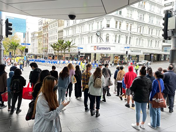 2022年6月25日國際反酷刑日前夕，澳紐150多名法輪功學員在奧克蘭皇后大街遊行。路人聚集觀看。（馬蘭花/大紀元）