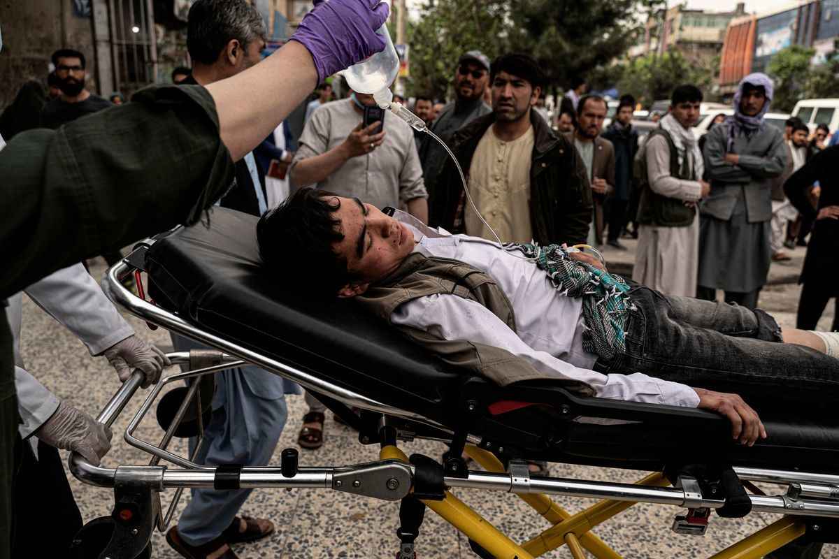 2022年4月19日，阿富汗首都喀布爾一家醫院外，醫務人員將一名受傷的青年抬上擔架。兩宗炸彈爆炸襲擊了什葉派哈扎拉社區的一所男校，造成至少6人死亡，17人受傷，包括學生。（Wakil Kohsar/AFP via Getty Images）