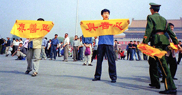 1999年7月，中共對法輪功發動滅絕性的迫害後，成千上萬的法輪功學員冒著生命危險在北京天安門廣場上和平請願，打出寫著中文「真善忍」的橫幅。圖中顯示一名準備抓人的中共警察，手上還拿著從其他學員手中奪下的橫幅。（明慧網）