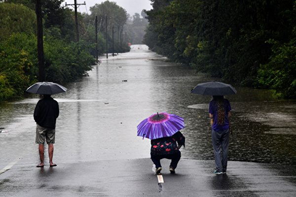 2021年3月22日，澳洲里士滿（Richmond）郊區，三位居民看著被洪水淹沒的道路。（SAEED KHAN/AFP via Getty Images）