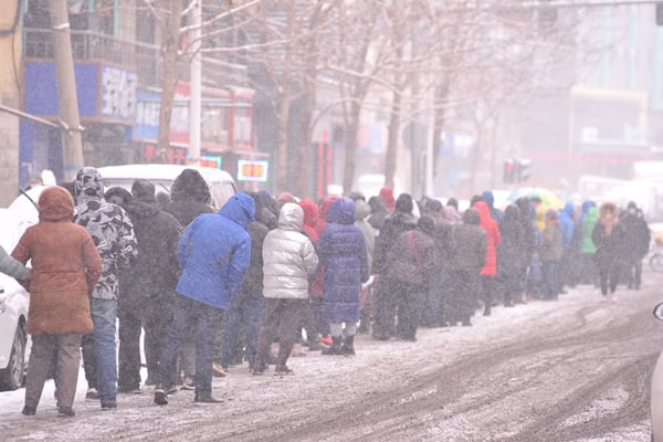 2022年3月2日，中國東北黑龍江省哈爾濱市下雪，人們在排隊做核酸測試。（STR/AFP via Getty Images）