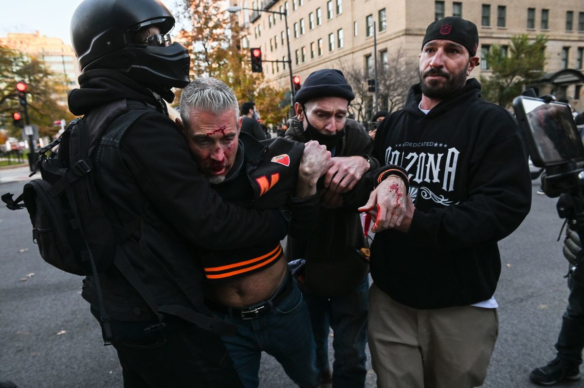 11月14日，在華府支持特朗普總統的大型集會後，特朗普總統的支持者（左二）被反特份子暴力攻擊和踢打致滿臉鮮血。（Roberto SCHMIDT/AFP via Getty Images）