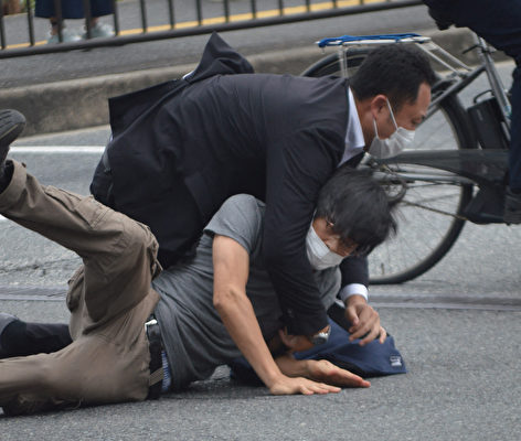 2022年7月8日，一名涉嫌槍殺日本前首相安倍晉三的男子（下）被警察撲倒在地。 （STR / Yomiuri Shimbun / AFP）