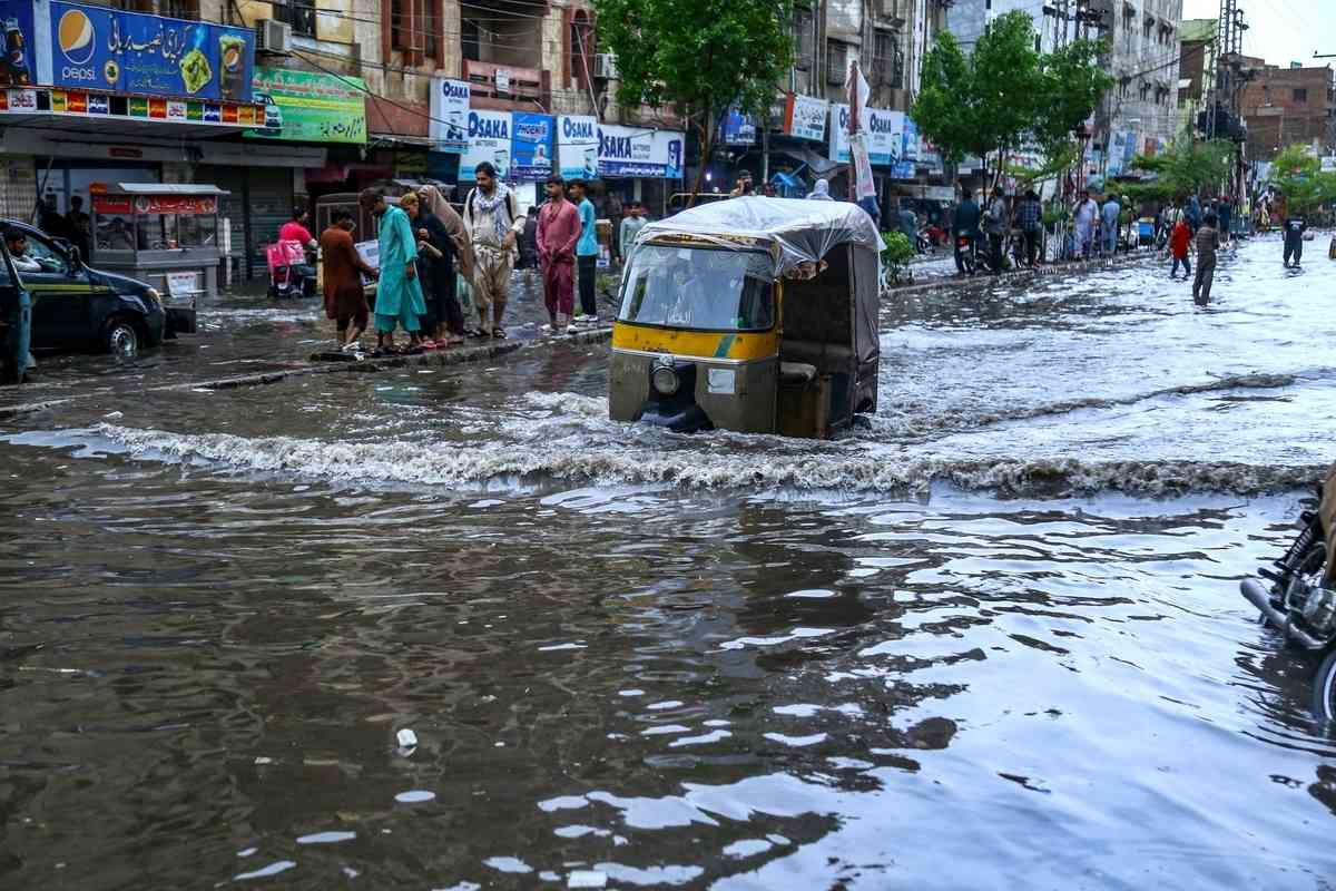 2025年7月14日,巴基斯坦信德省海得拉巴市(Hyderabad)遭暴雨襲擊後,民眾被迫涉水出行。(Jan Ali Laghari/Middle East Images/AFP via Getty Images)
