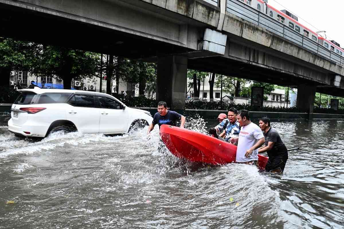 2026年8月17日，菲律賓首都馬尼拉遭暴雨襲擊後，幾名志願者使用塑膠船協助轉移一名被洪水圍困的居民。（Ted Aljibe/AFP via Getty Images）