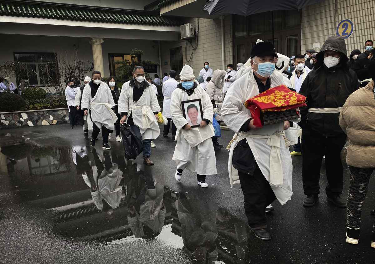 2023年1月14日，中國上海的一場葬禮上，穿著白色喪服的送葬者捧著親人的骨灰。（Kevin Frayer/Getty Images）