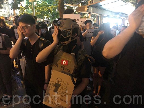 2019年8月30日晚上8點，香港民眾在中環和平紀念碑舉辦重光紀念日默站活動，參與民眾做出掩右眼手勢。（梁珍／大紀元）
