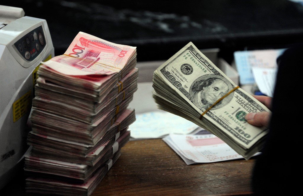 圖為中國安徽省合肥市一家銀行，一名工作人員正在清點一疊美元和一疊人民幣。（STR/AFP）
