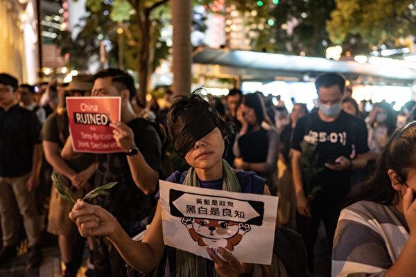 2019年8月30日晚上8點，香港民眾在中環和平紀念碑舉辦重光紀念日默站活動，參與民眾遮掩了右眼。（Anthony Kwan/Getty Images）