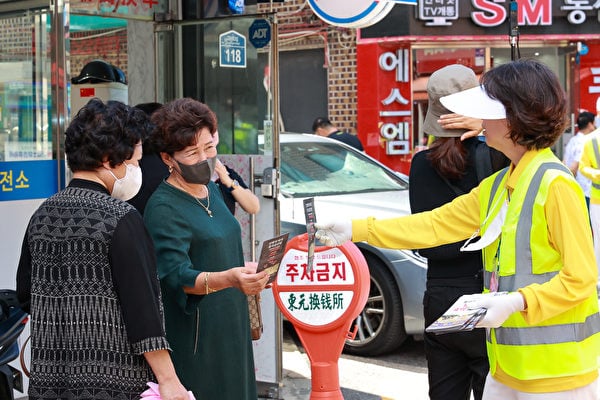 遊行隊伍經過南韓首爾中國人聚居地，民眾接過義工分發的真相傳單。（金國煥／大紀元）