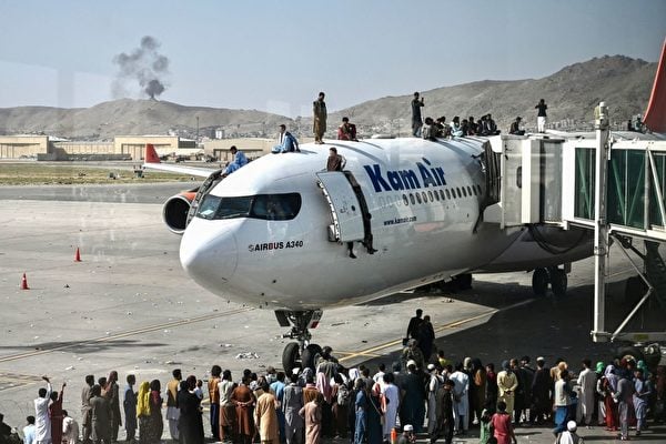 2021年8月16日，阿富汗民眾在喀布爾機場等待逃離時，爬上一架飛機。（WAKIL KOHSAR/AFP via Getty Images）