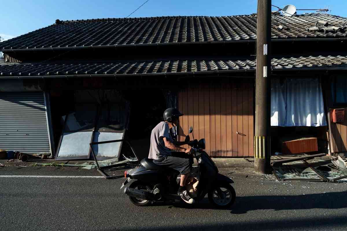 2026年7月29日，日本熊本縣八代市，一名男子騎車經過一棟受損的房屋。（Tomohiro Ohsumi/Getty Images）