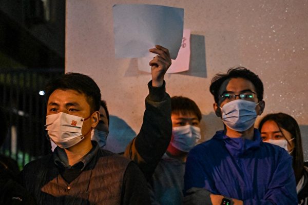 2022年11月27日，上海民眾舉著白紙進行無聲抗議。有民眾說，不需要在上面寫任何東西。這是人民革命的象徵。（Hector RETAMAL / AFP）