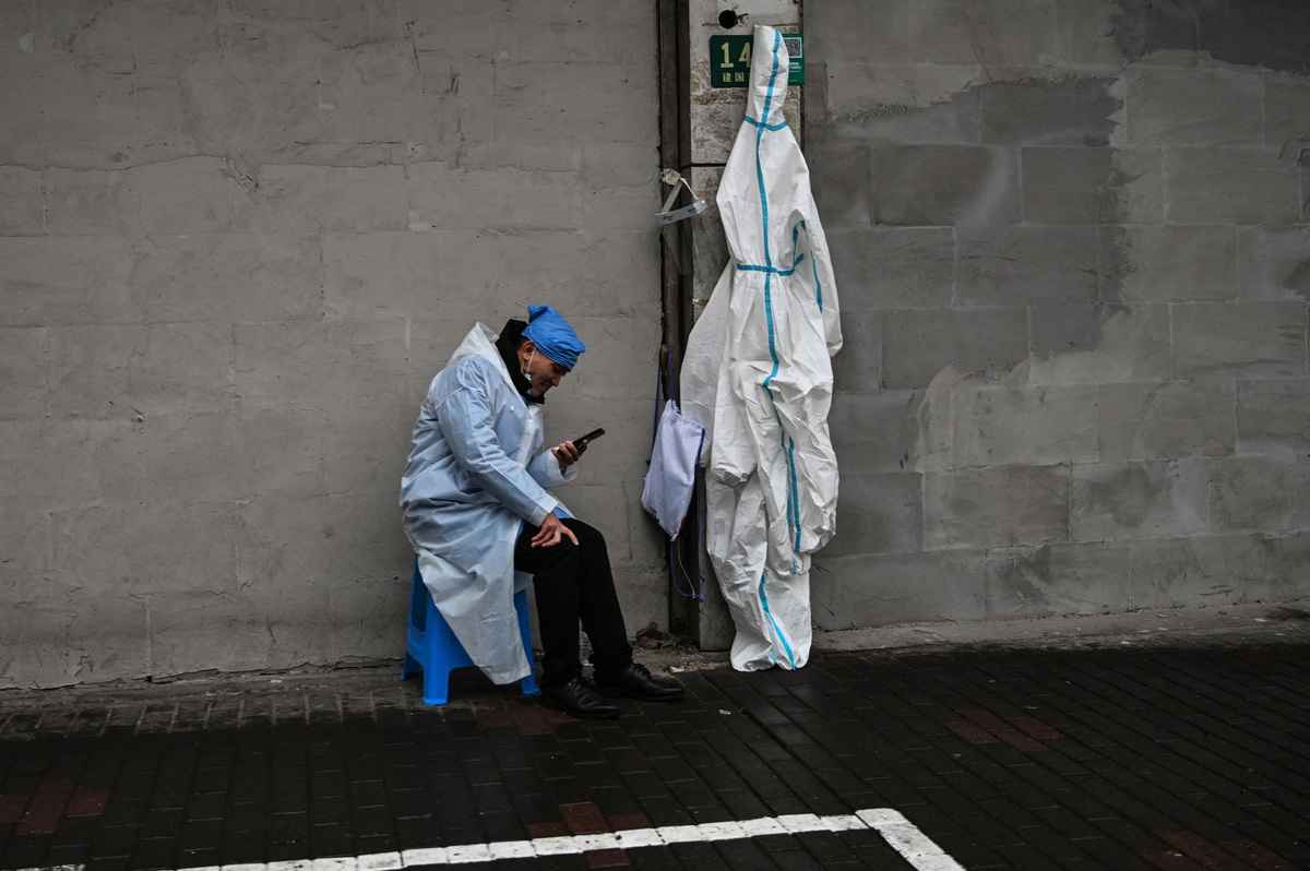 上海封城加劇晶片供應鏈緊張。圖為上海黃浦區一名防疫人員查看手機。（Hector Retamal / AFP）