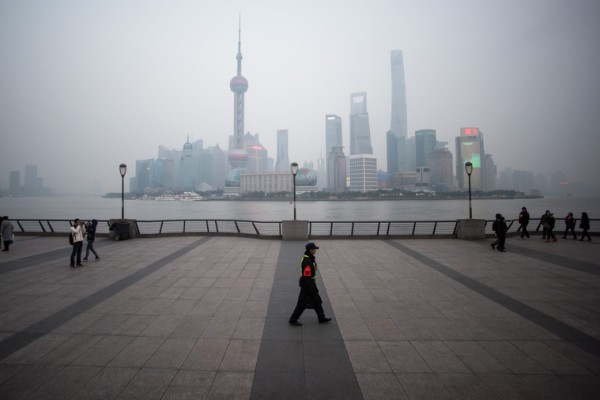 2016年1月18日，中國上海，一名保安走在橫跨浦東新區金融區的黃浦江外灘。（JOHANNES EISELE/AFP）