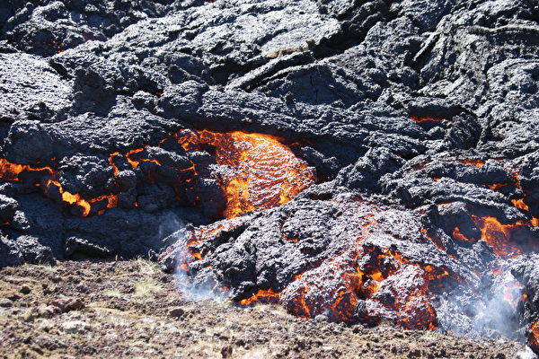 2022年8月4日，冰島法格拉達爾山（Fagradalsfjall）附近，梅拉達利爾（Meradalir）山谷的火山噴發，熔岩在地面流動。（Jeremie Richard/AFP）