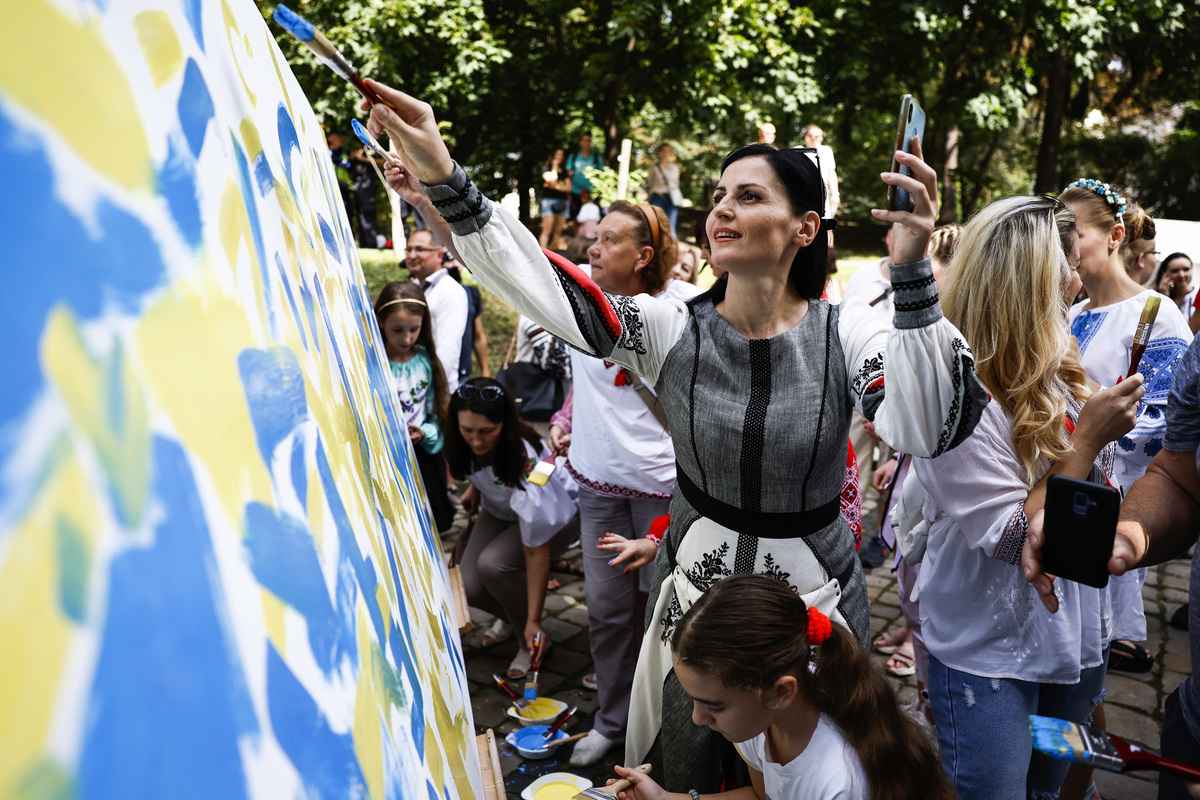 2022年8月24日，烏克蘭利沃夫（Lviv），在烏克蘭獨立日紀念活動期間，民眾在一面白色帆布上塗上代表烏克蘭國旗的藍色和黃色塗料。（Jeff J Mitchell/Getty Images）