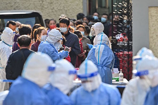 2022年3月23日，在上海的一個大院中，穿著防護裝備的衛生工作者在對人們進行COVID-19檢測前準備設備。 （HECTOR RETAMAL/AFP via Getty Images）