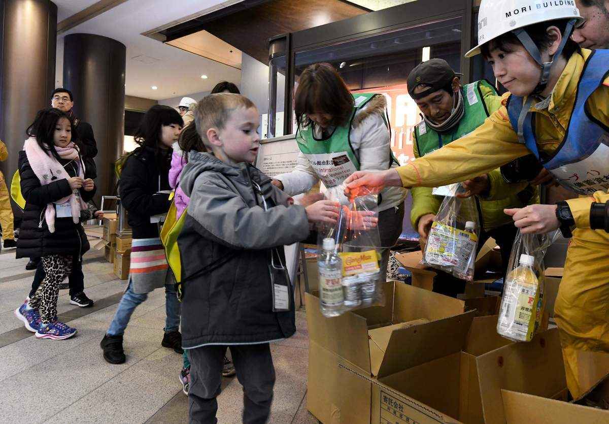 資料圖：2018年1月17日，在造成6,400多人死亡的阪神大地震23周年之際，一所國際學校的兒童在東京六本木山（Roppongi Hills）商業和購物區的災難演習中領取食物和水。包括一所國際學校的學生在內的約100人參加了年度災難演習。（TORU YAMANAKA/AFP via Getty Images）