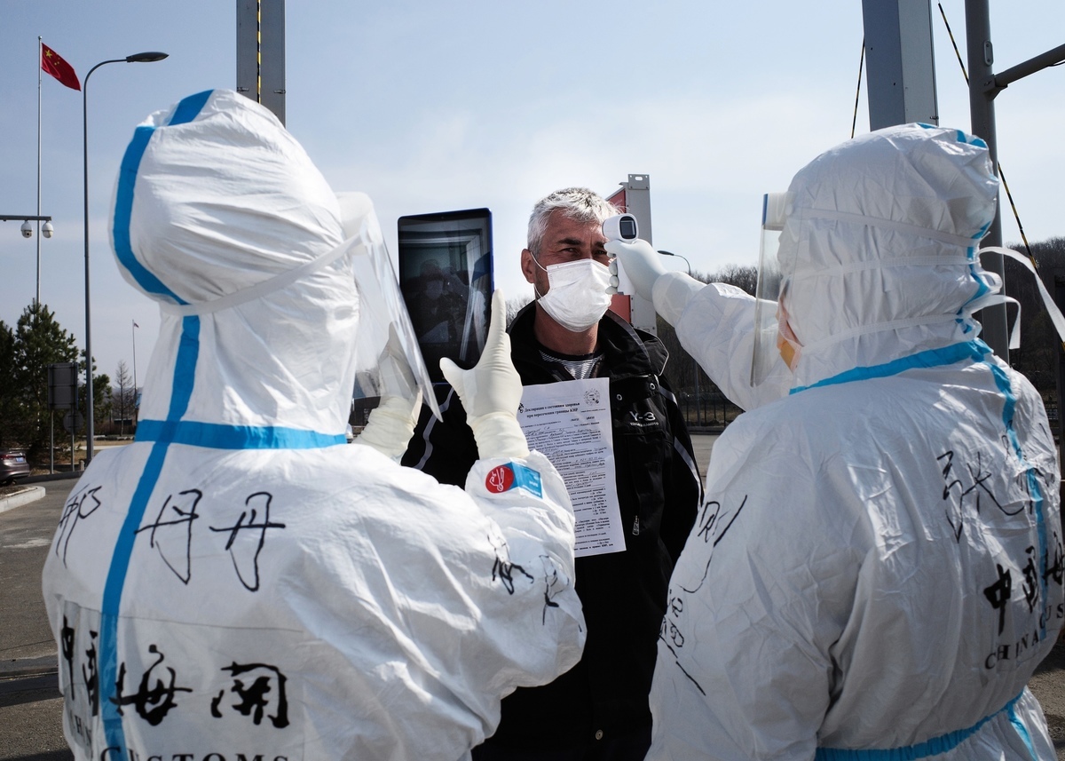 圖：2020年5月1日，黑龍江省綏芬河邊境海關檢查站，為預防新冠肺炎疫情，工作人員穿著防護服檢查進境俄羅斯司機體溫。（STR/AFP via Getty Images）