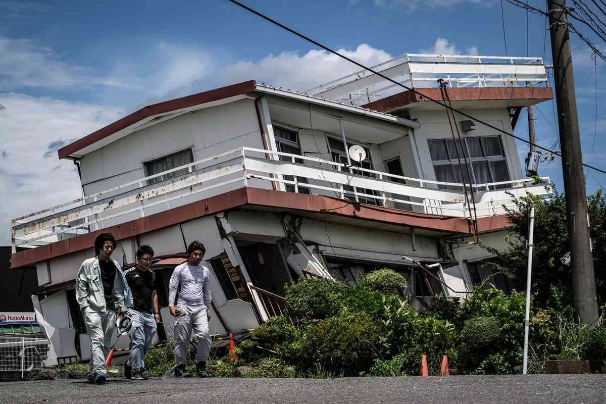 2026年7月29日，日本熊本縣八代市，幾名工人走過一棟在地震中嚴重受損的房屋。（Yuichi Yamazaki/AFP via Getty Images）
