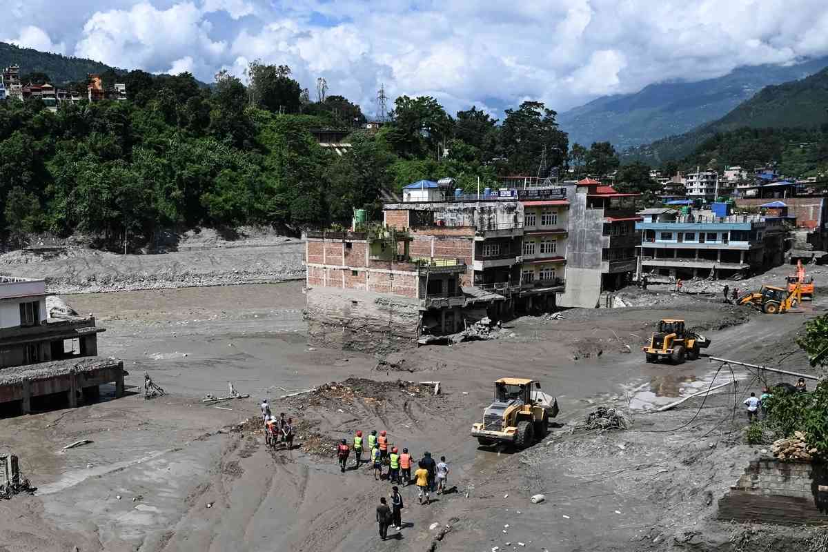 2026年8月27日，在尼泊爾努瓦科特縣（Nuwakot）特里蘇里（Trishuli）發生山洪的第二天，工人使用挖土機清理道路上的淤泥和各種垃圾。（Arun Sankar/AFP via Getty Images）
