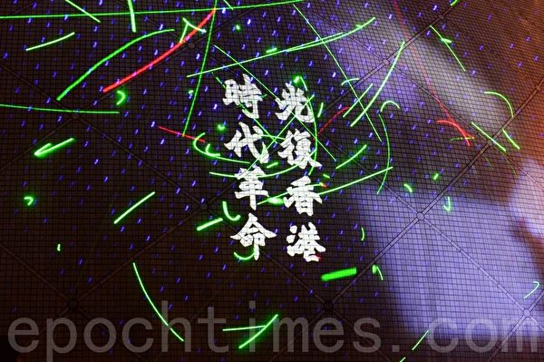 圖為2019年8月7日，尖沙咀太空館，民眾揮舞雷射筆聲援被捕的香港浸會大學學生會長方仲賢，並將「光復香港，時代革命」的標語投射在太空館的外牆上。（宋碧龍／大紀元）