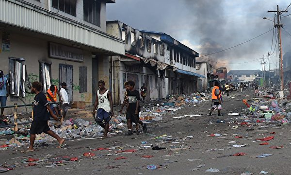 2021年11月26日，人們走過所羅門群島霍尼亞拉的唐人街區，在經歷了第三天的暴力事件之後，所羅門總理的家遭到襲擊。（CHARLEY PIRINGI/AFP via Getty Images）