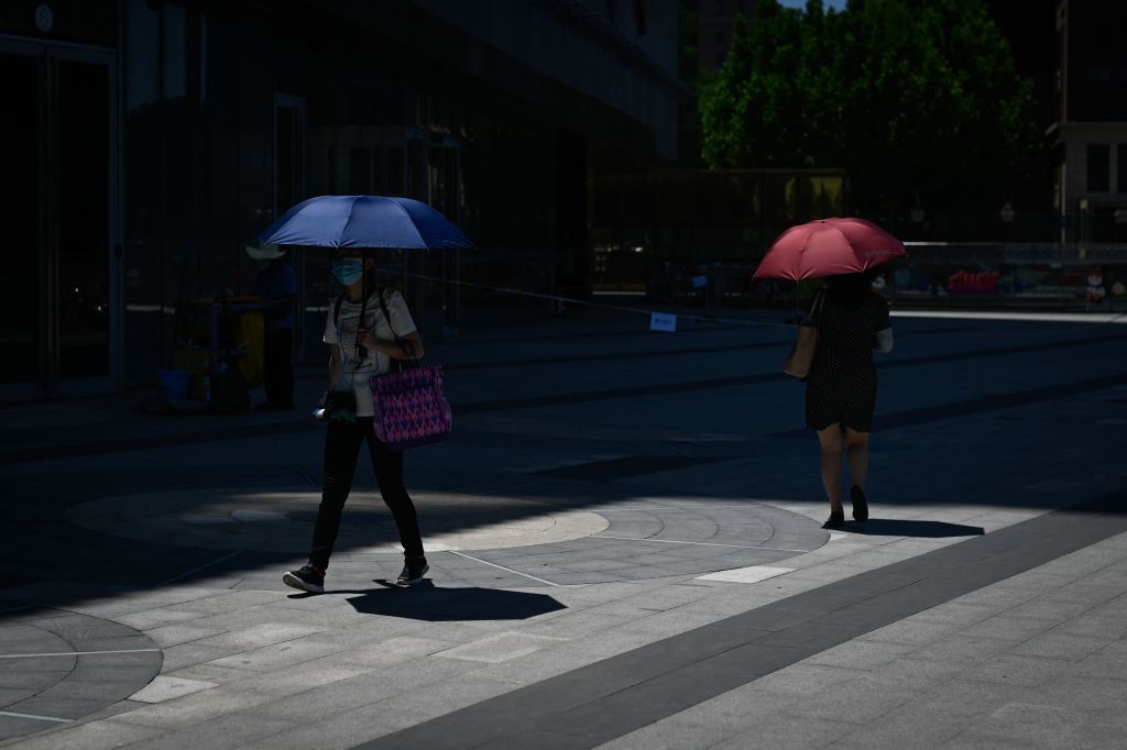 2022年6月24日，走在北京街頭的女士打著陽傘。（WANG ZHAO/AFP via Getty Images）