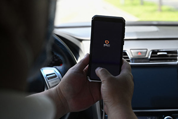 圖為2021年7月2日，北京一名司機在智能手機上打開滴滴出行App。 （Jade GAO/AFP）