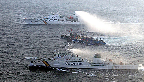 圖為2010年12月22日,南韓海警船發射水砲阻止中國漁船(中間)非法捕魚。(Photo credit should read PARK YOUNG-CHUL/AFP via Getty Images)