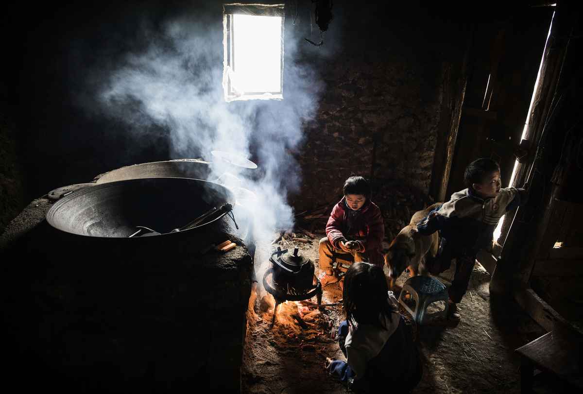 2016年12月17日，貴州省安順市的三名留守兒童圍坐在火堆旁取暖。這些農村兒童由爺爺奶奶撫養長大，而他們的父母則在城市裏尋找工作。（Kevin Frayer/Getty Images）