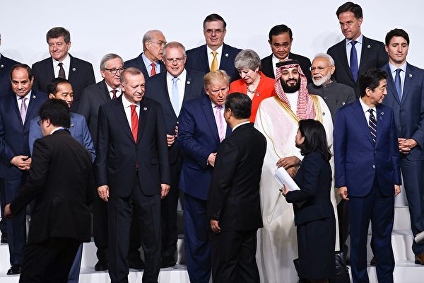 2019年6月28日，特朗普總統與習近平在G20峰會拍大合照前握手。（BRENDAN SMIALOWSKI/AFP/Getty Images）