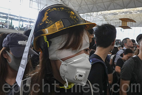 2019年8月12日，港人在香港機場展開「警察還眼」集會。圖為一位女子在右眼貼上紗布，以聲援11日眼睛受傷的女子。（余鋼／大紀元）